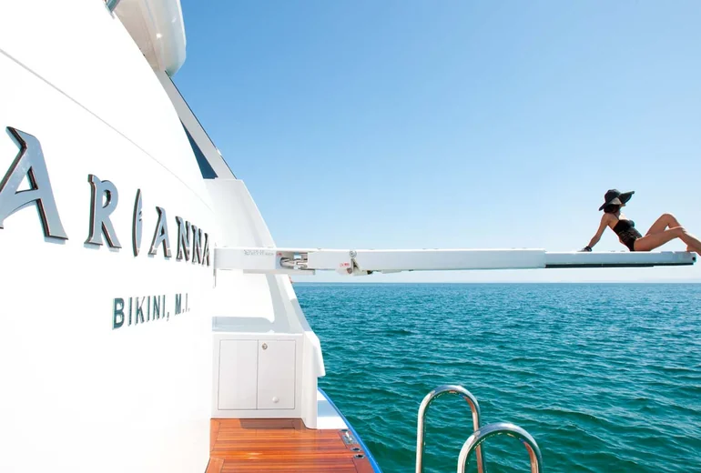 Adults relaxing on a charter yacht aft deck with a floating lounge in the water below