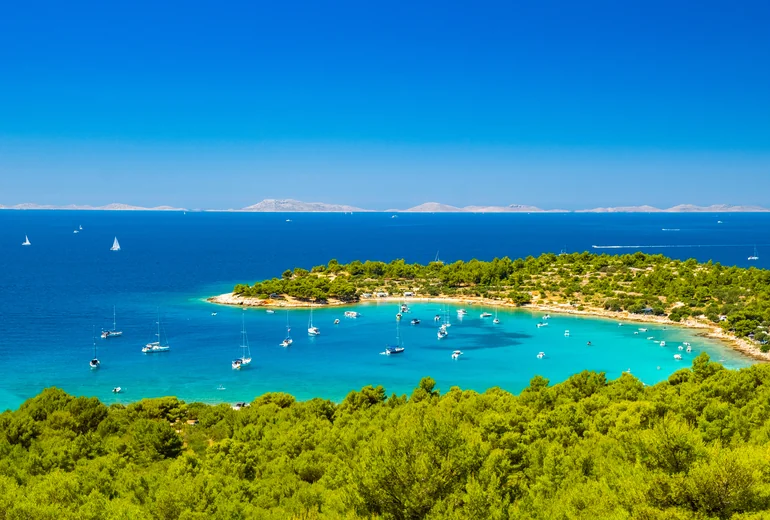 Catamaran at anchor in clear Croatian water with the dinghy alongside