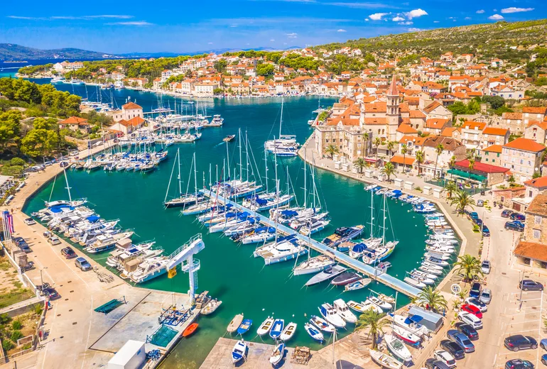 Aerial of Milna marina and a stone village with a church tower on Brač island