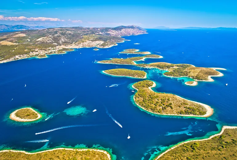 Aerial of the Pakleni islands with motorboat wakes and the Hvar coastline behind