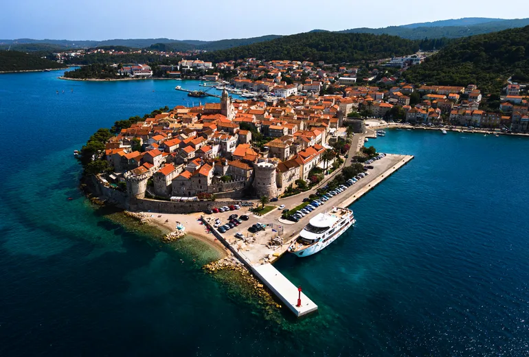 Aerial of the walled Korcula old town peninsula with harbour and pier