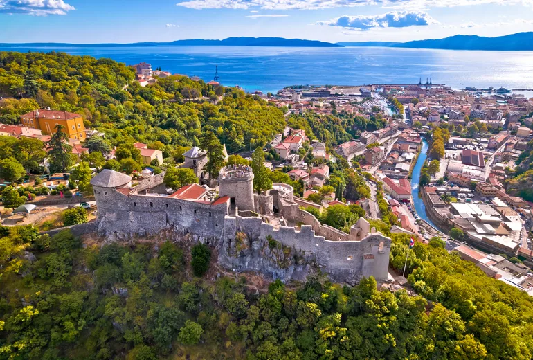 Aerial of Trsat castle on a wooded hill above Rijeka and the Kvarner bay