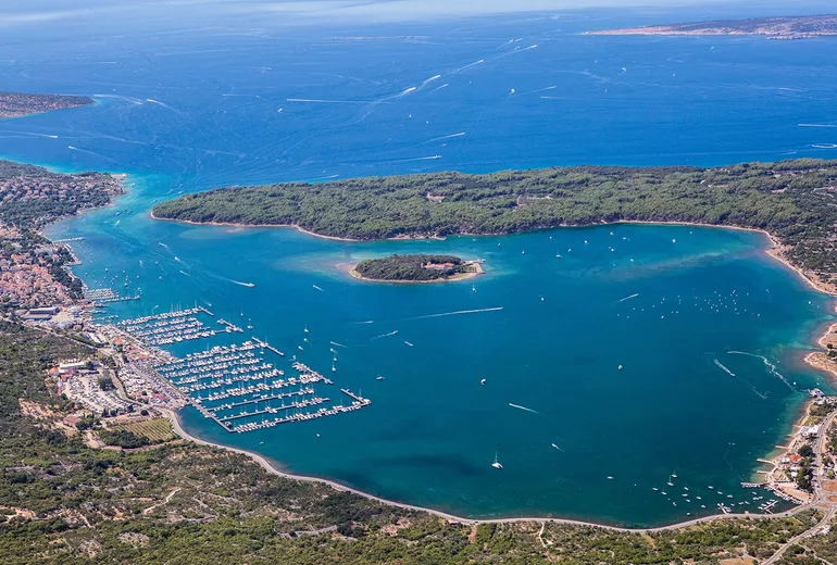 High aerial of Punat bay on Krk with a large marina and a wooded islet