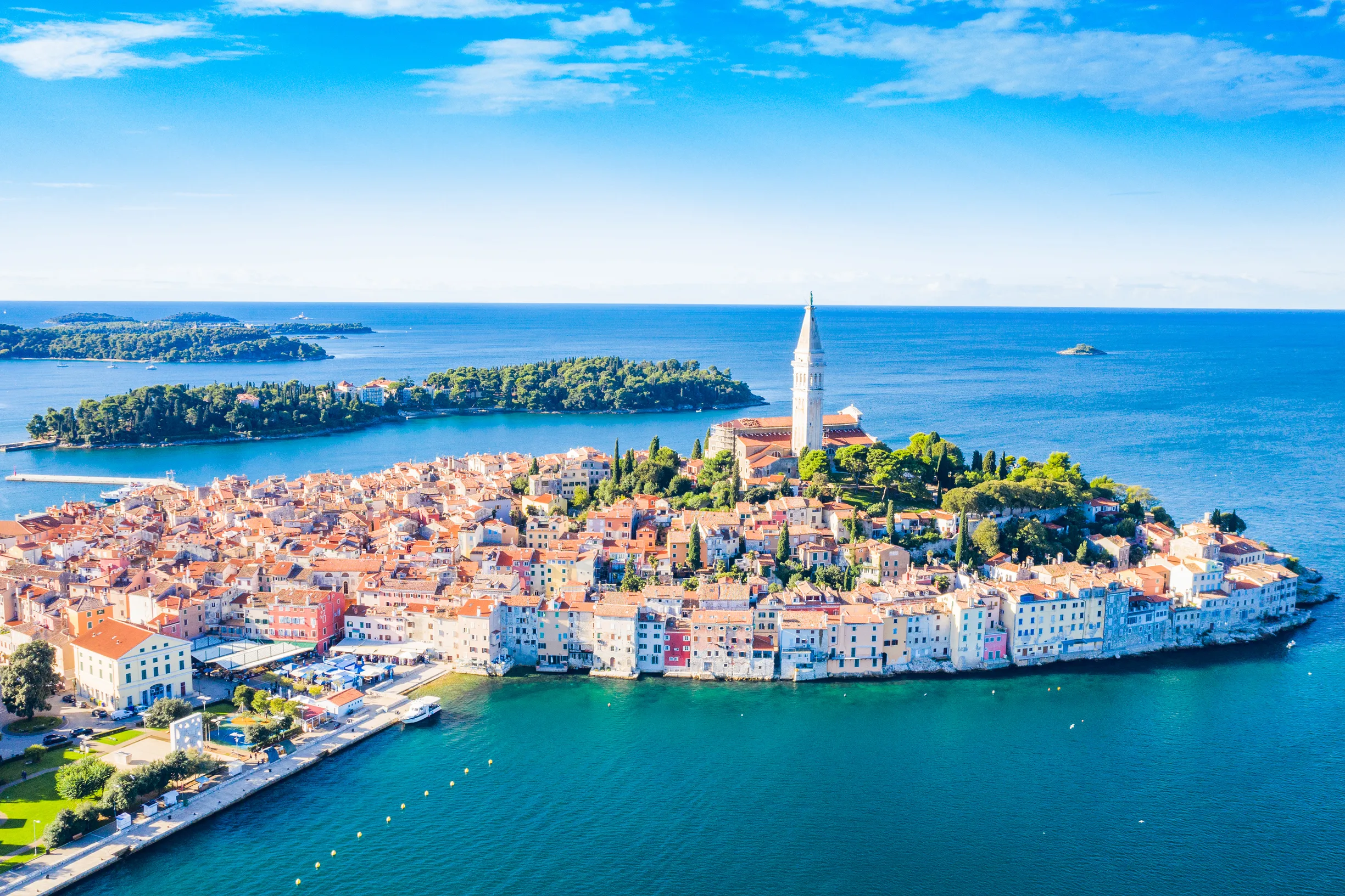 Aerial of Rovinj old town peninsula, bell tower and wooded offshore islands