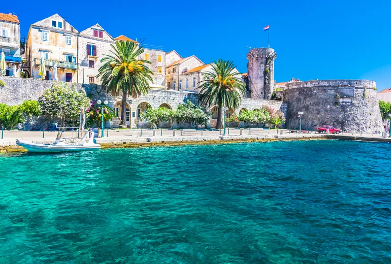 Korčula old town walls and towers above the clear turquoise waterfront