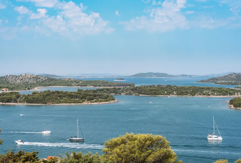 Motorboats and sailboats cruising island-dotted turquoise channels on a hazy summer day