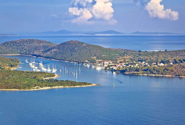 Row of sailboats moored in a sheltered channel beside a small island village